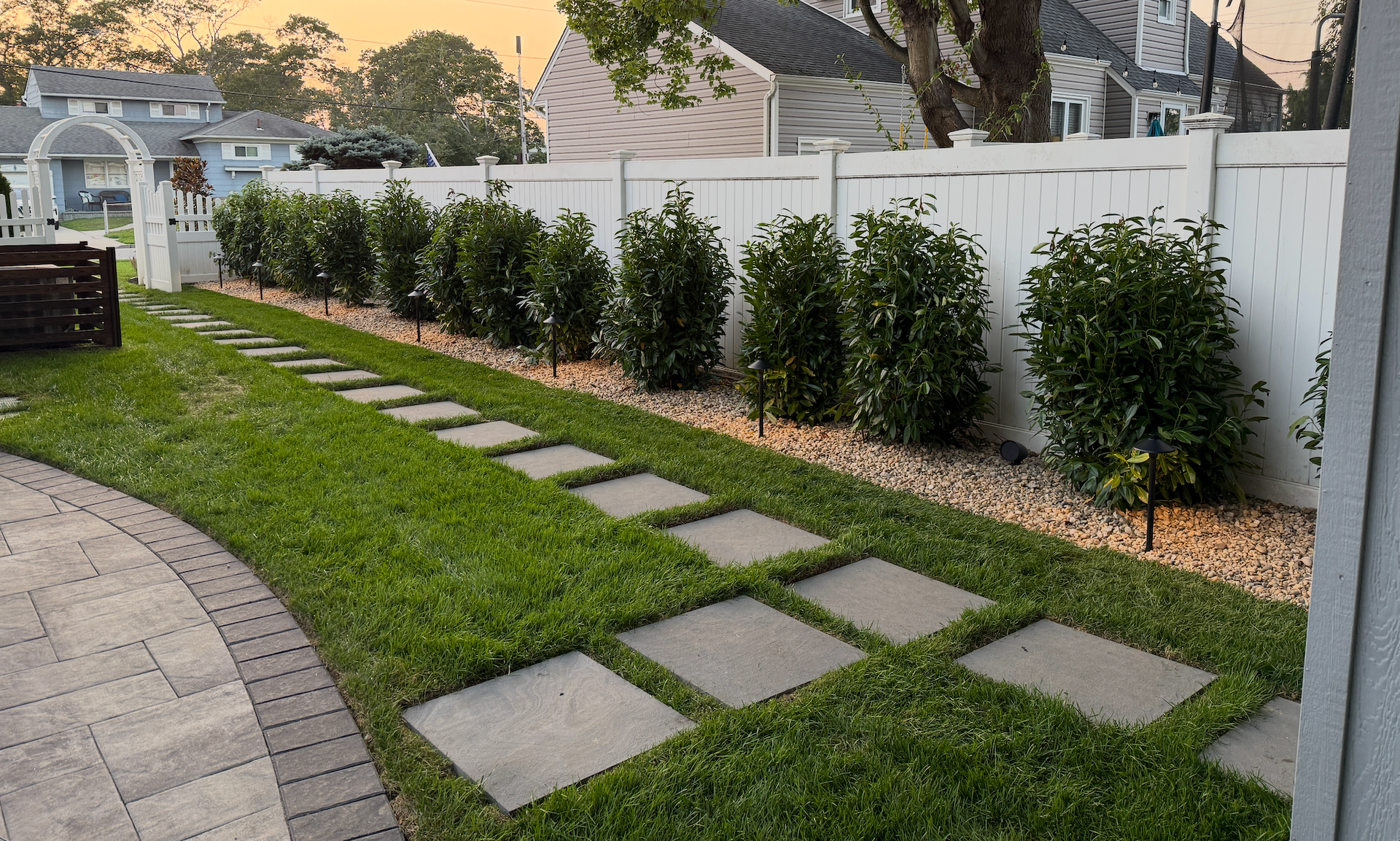 Geometric stone walkway with green grass inlays forming diamond patterns beside water