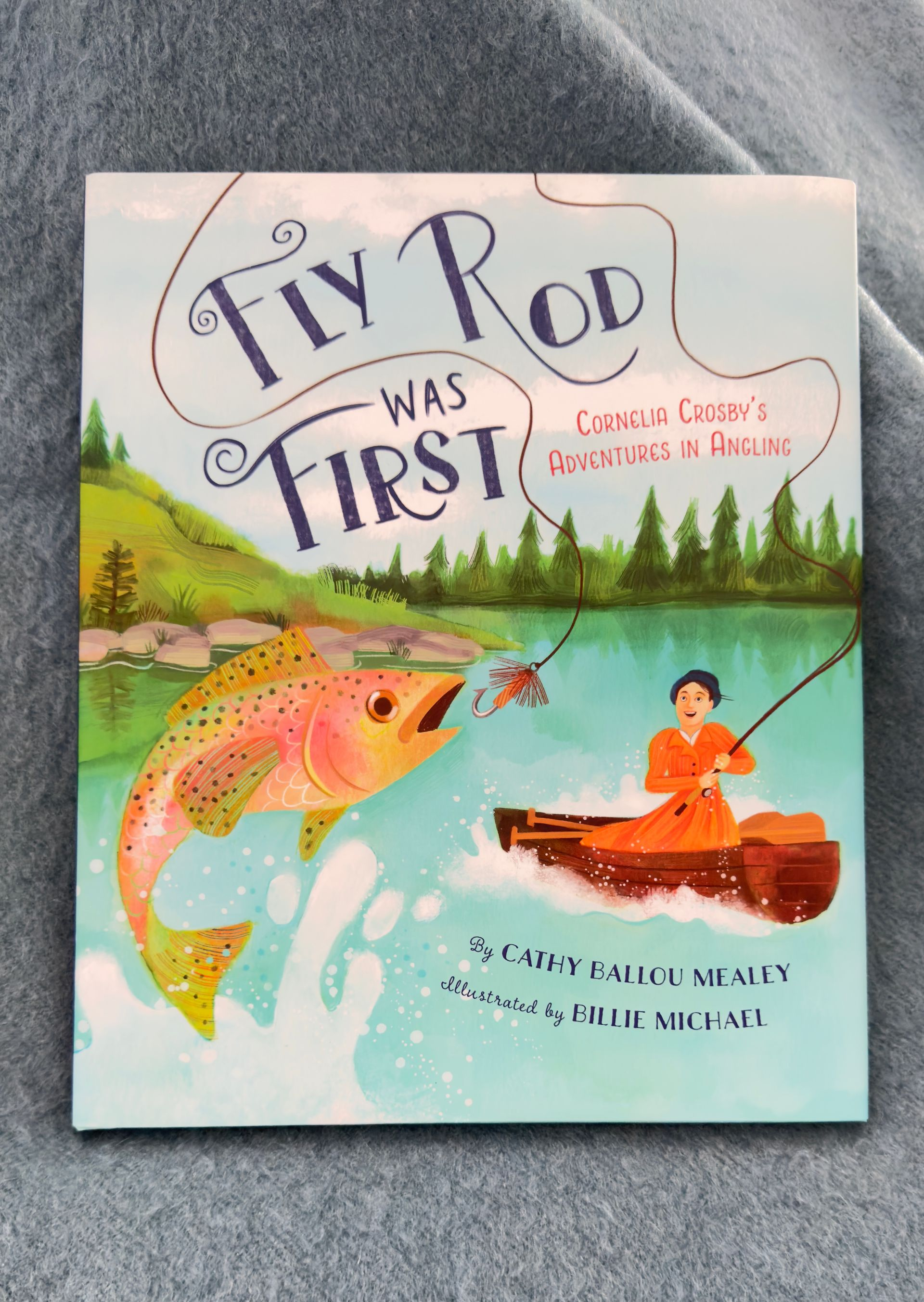 Book cover with fish leaping at a boy fishing in a canoe on a lake at sunset. The book is called Fly Rod was First