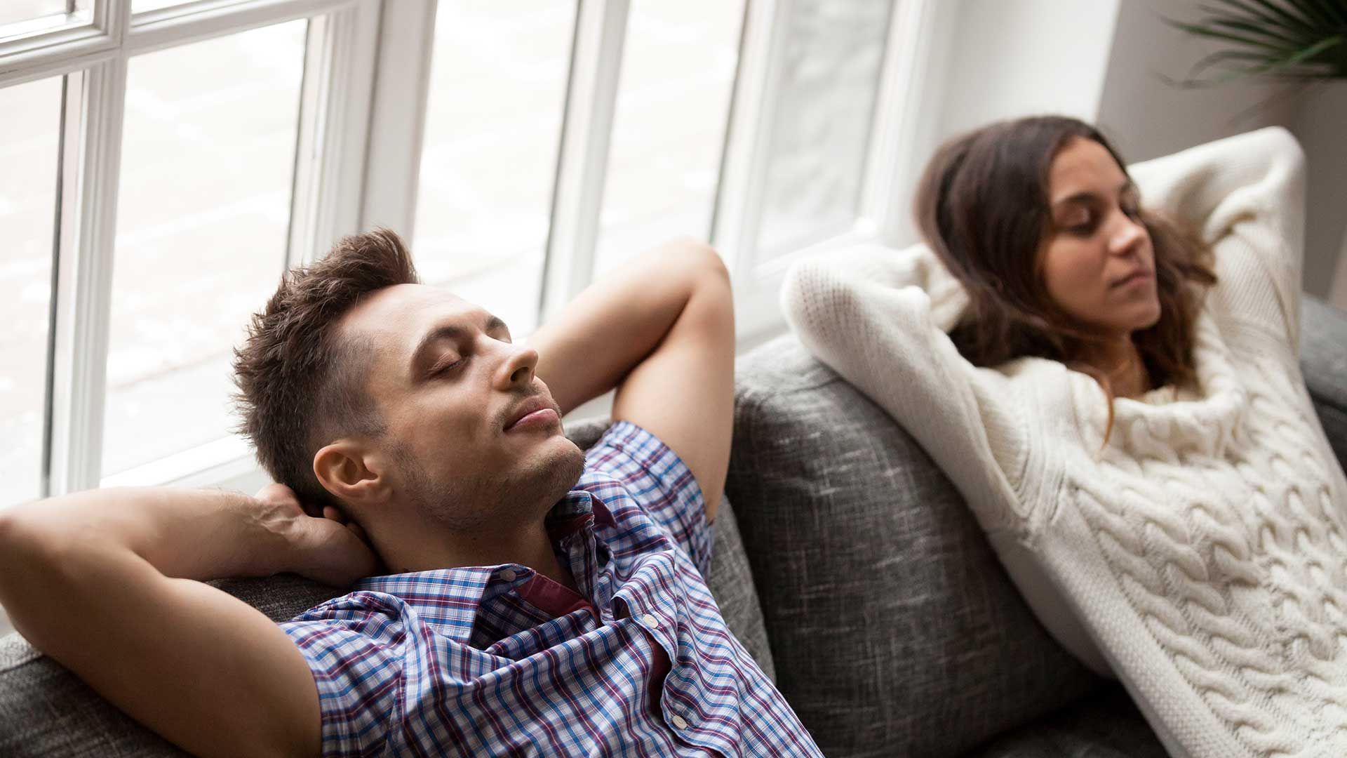 a man and a woman are sitting on a couch living comfortably
