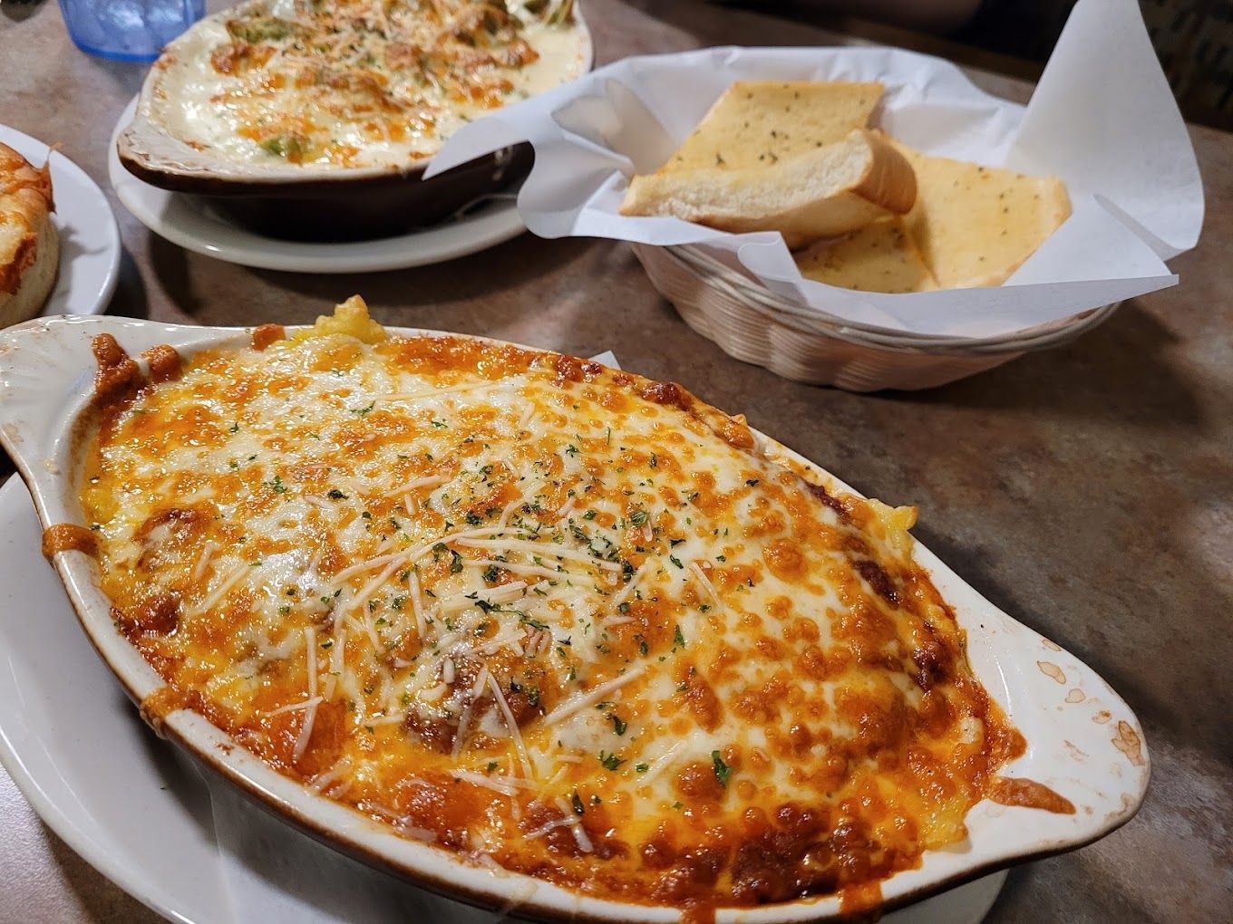 A casserole dish of a baked pasta dinner and garlic bread.