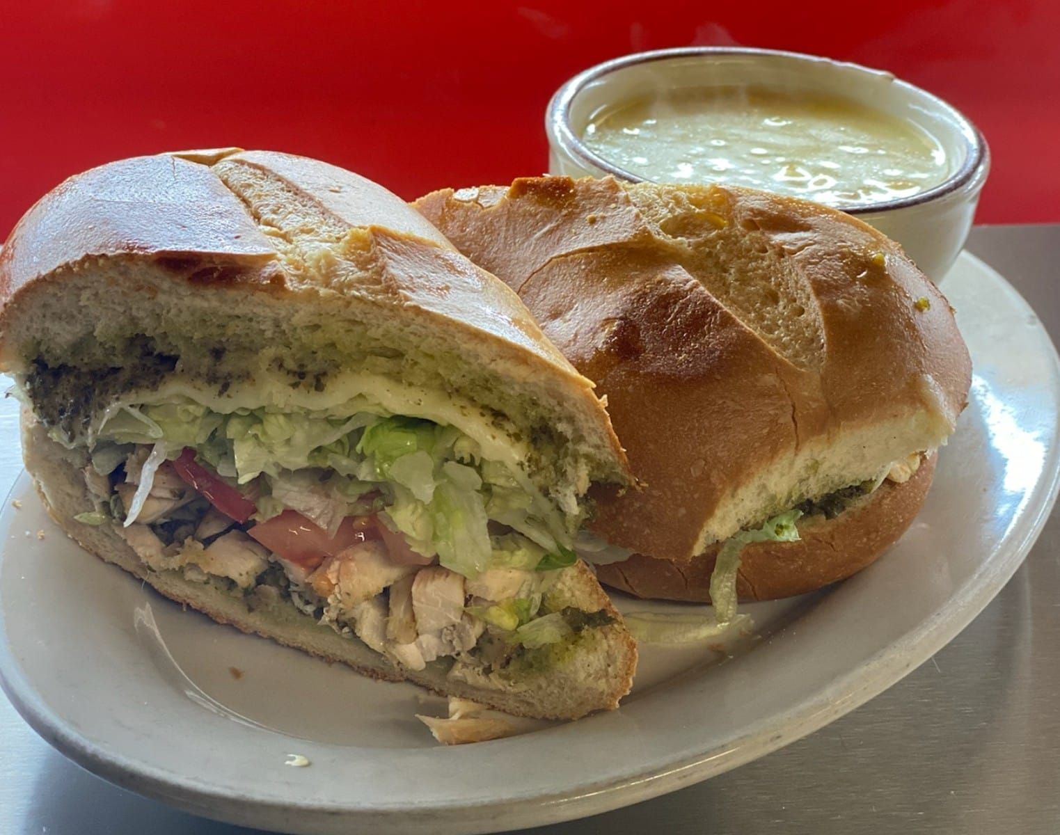 A sandwich and a bowl of soup are on a white plate.