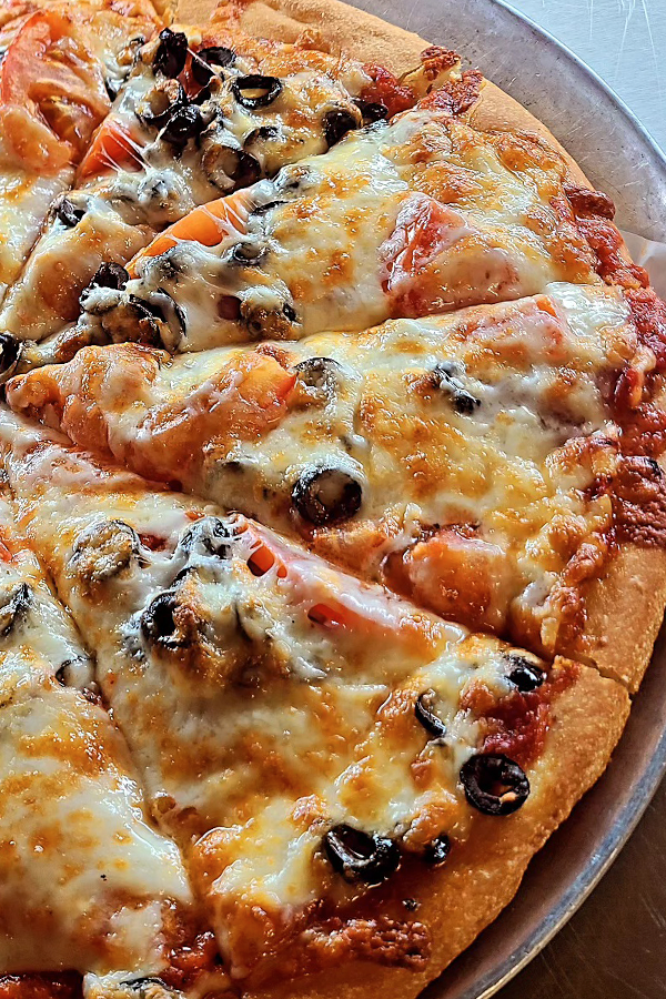 A pizza with tomatoes , olives and cheese 