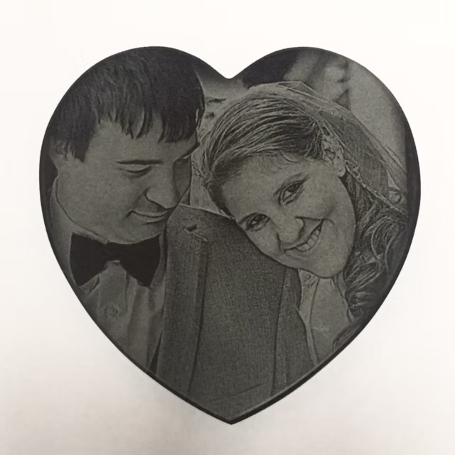 A black-and-white heart-shaped portrait of two smiling people leaning close together