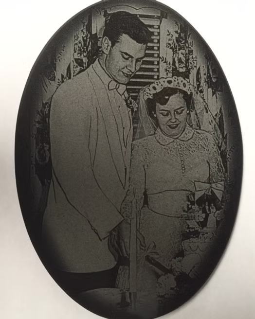 A couple stands over a cake at a table, preparing to cut it in a framed black-and-white photo.
