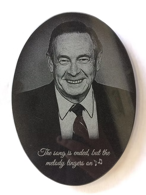 Oval black-and-white memorial portrait of a smiling man in a suit with a quote at the bottom.