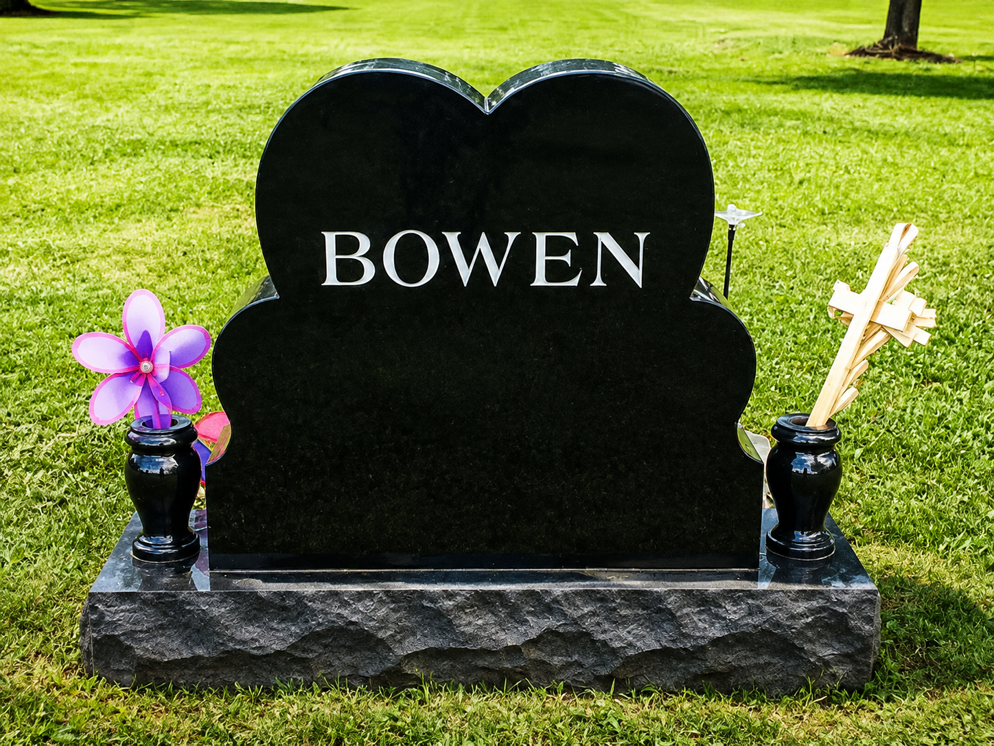 Gray granite gravestone engraved with the word “LOVE” in a grassy cemetery.