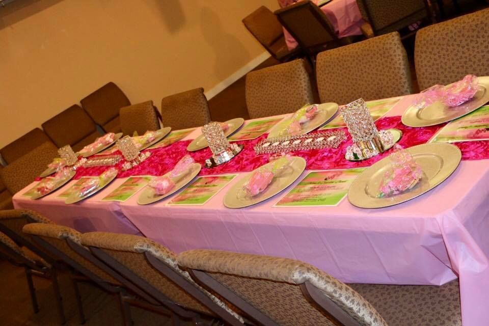 Banquet table set with plates, silverware, and pink decorations in a warmly lit dining room