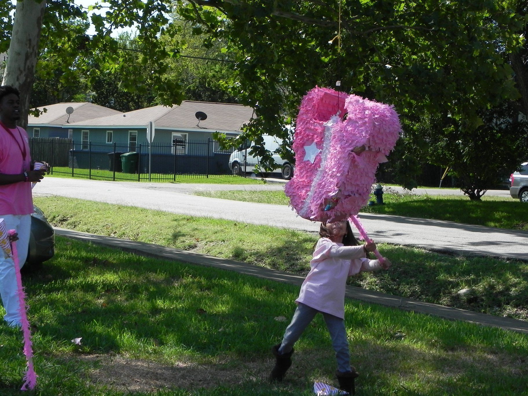Child carrying a large pink cotton candy on a stick in a sunny park