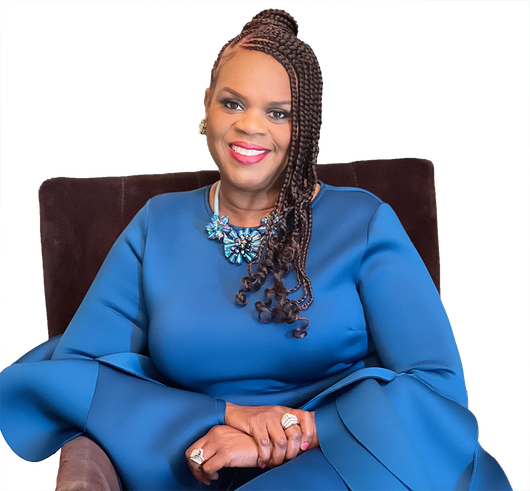 Smiling woman in a blue dress seated on a chair, wearing a statement necklace.