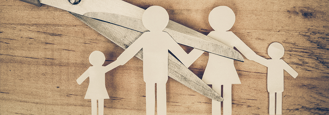 Scissors cutting a paper family, symbolizing divorce or separation.