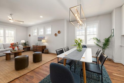Bright open living and dining room with gray sofas, woven accents, wood floors, and a white dining table