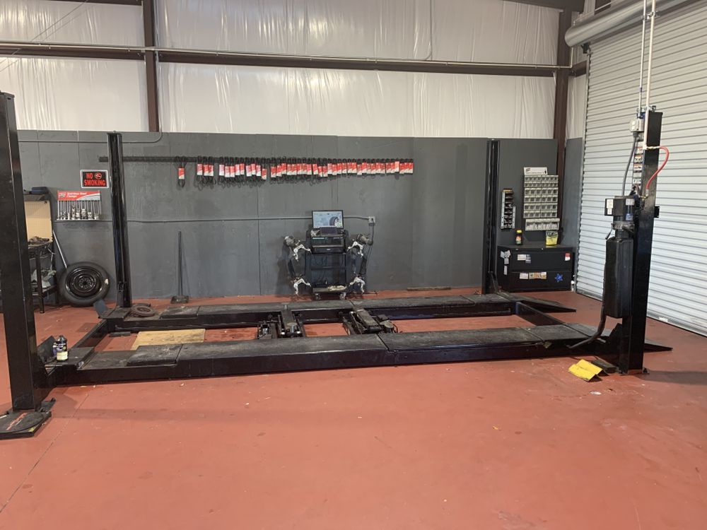 Auto repair shop with a vehicle lift and workbench inside a garage, with an orange floor and gray walls | Elite Auto Repair & Service Inc