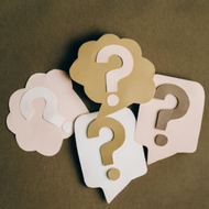 Thought bubbles with question marks in beige, white, and brown on a green background