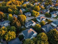 Aerial view of a suburban neighborhood with houses surrounded by dense green and orange trees.