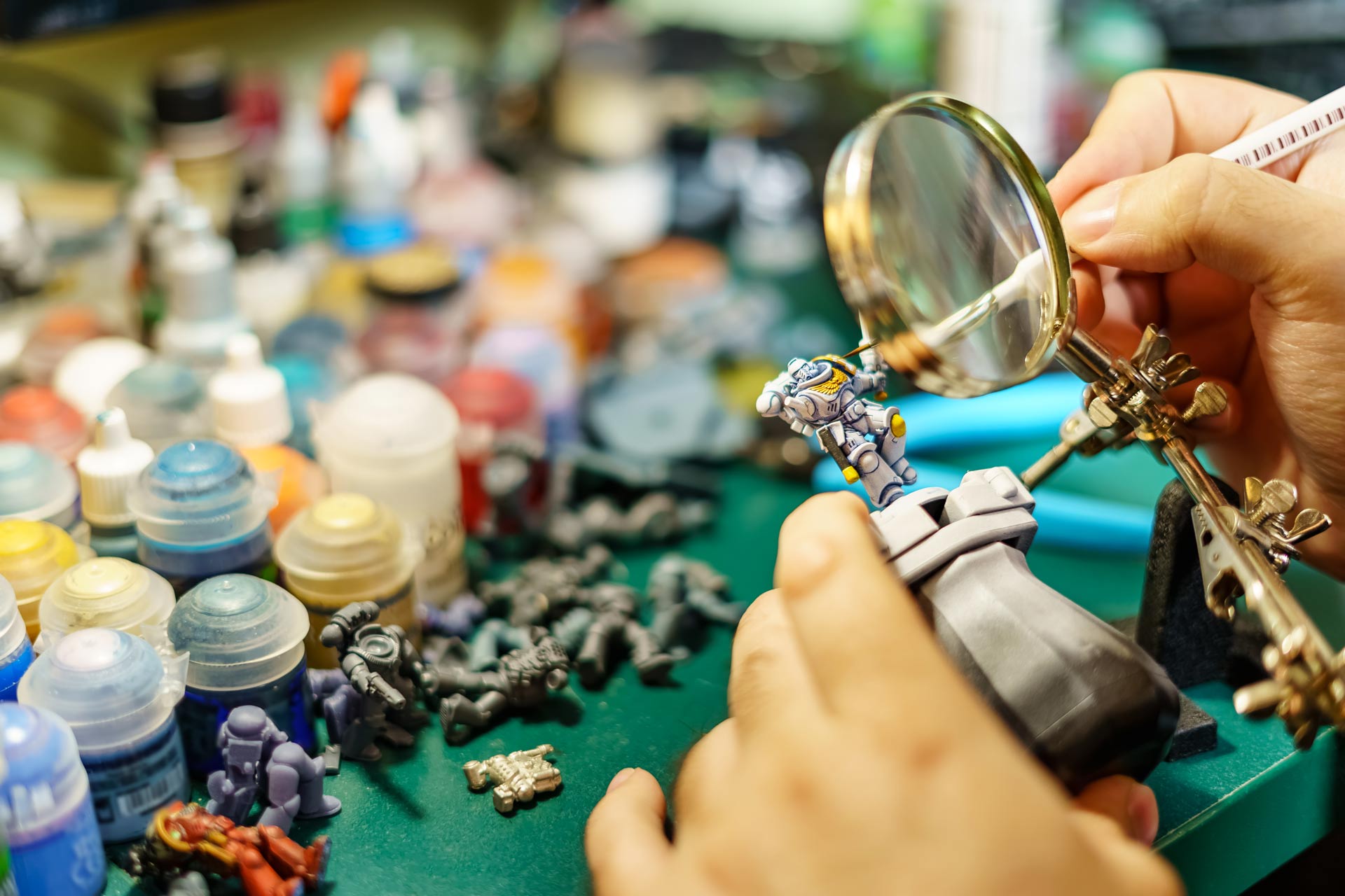 Man-painting-miniatures-of-board-game-with-large-magnifying-glass