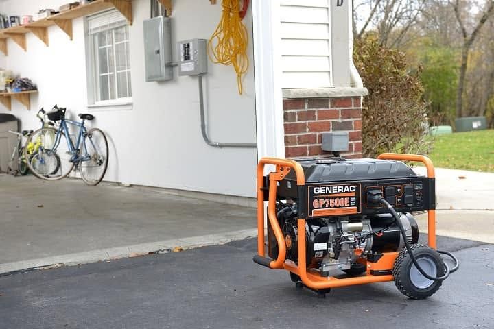 Orange generator on a driveway beside a house, with bicycles parked nearby.