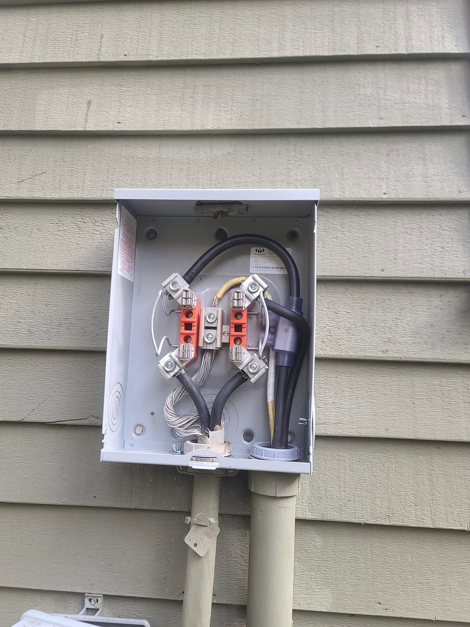 Open electrical junction box mounted on gray house siding, with exposed wires and connectors.