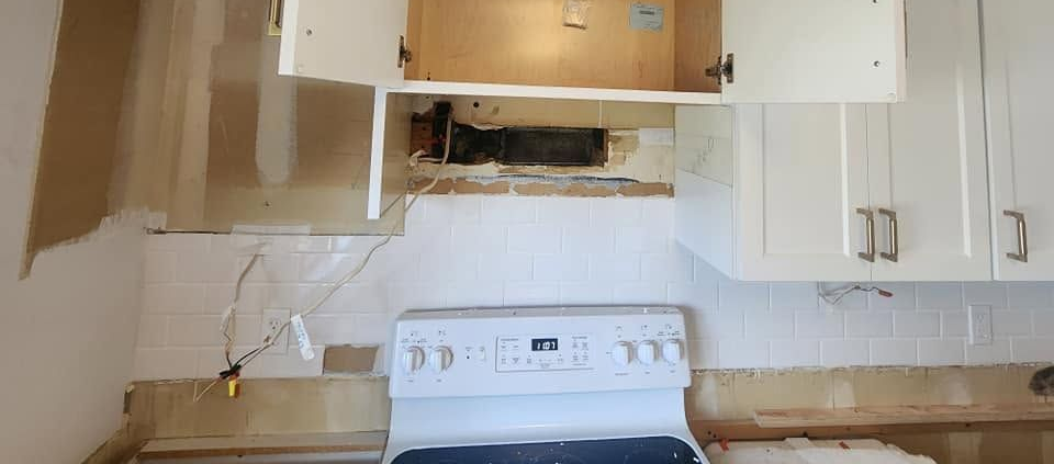 Small kitchen with white cabinets, stove, countertop, and an open cabinet above the range.