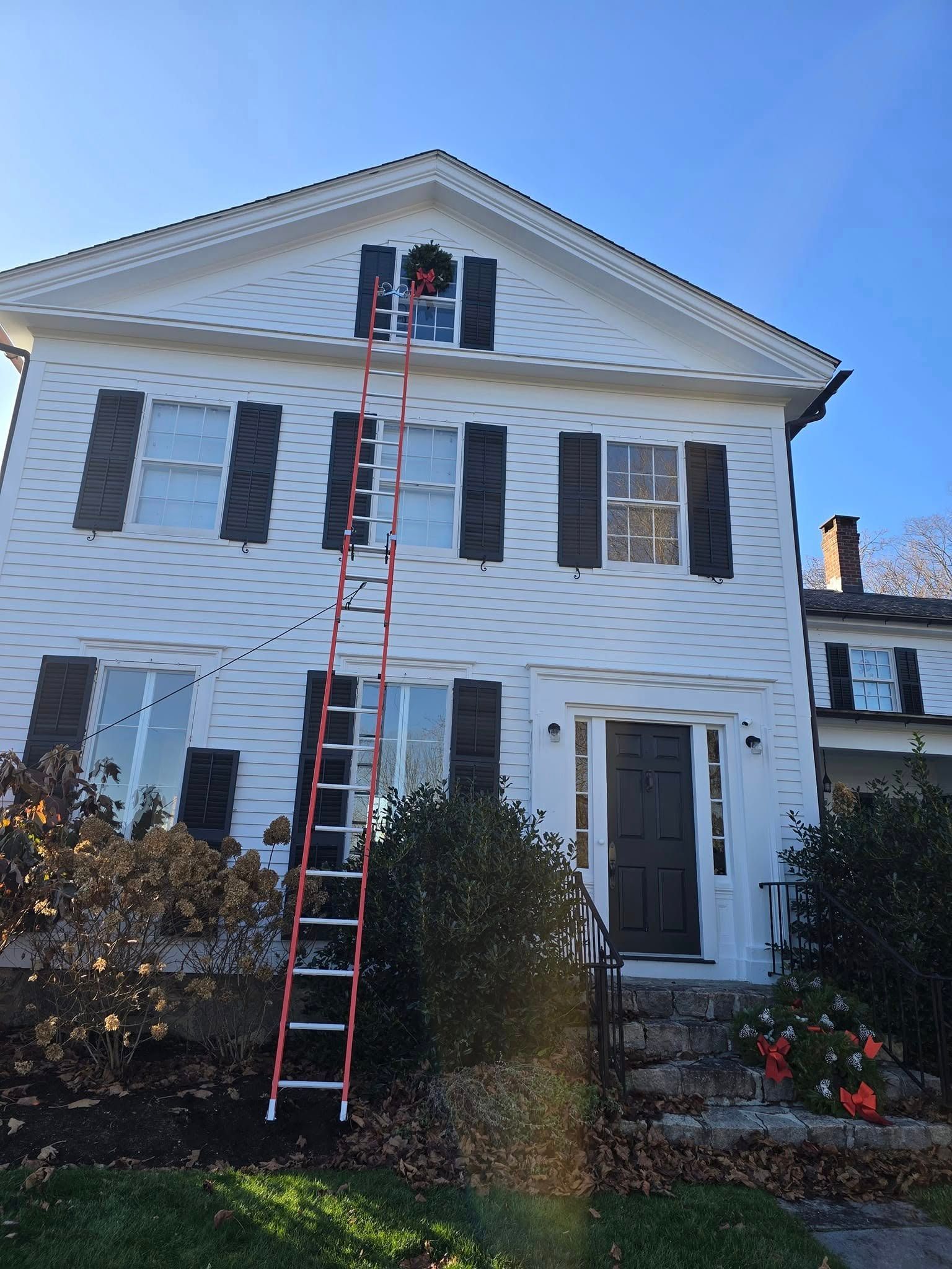 House with a red ladder reaching the roof under a blue sky