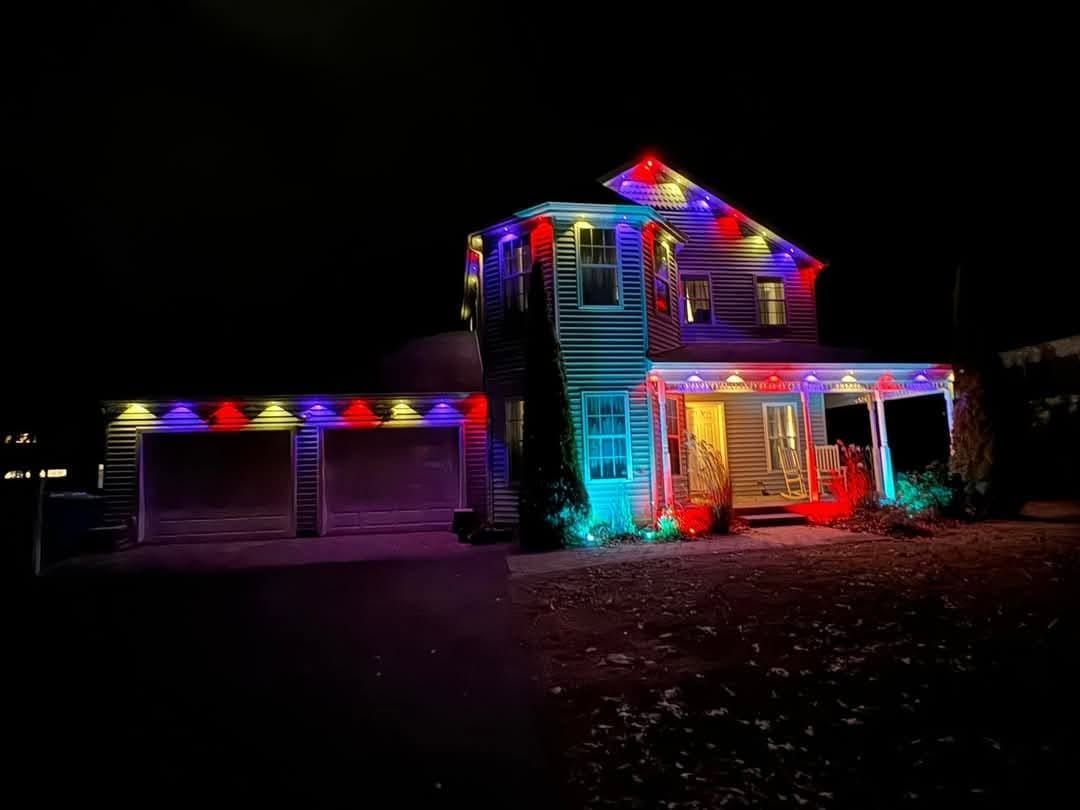 House decorated with colorful Christmas lights at night, with lit garage and front entrance