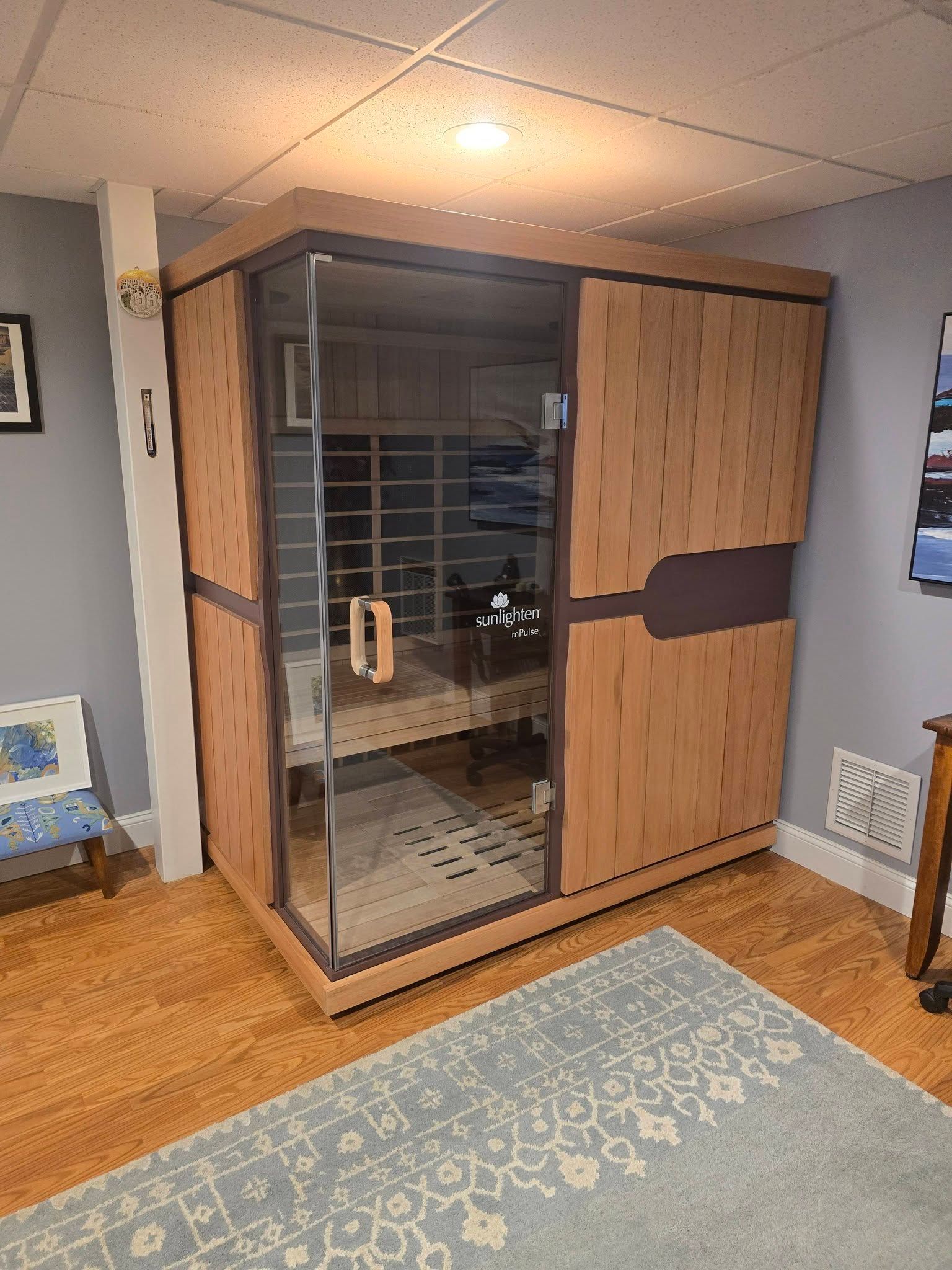Wooden indoor sauna cabin with glass door in a carpeted room