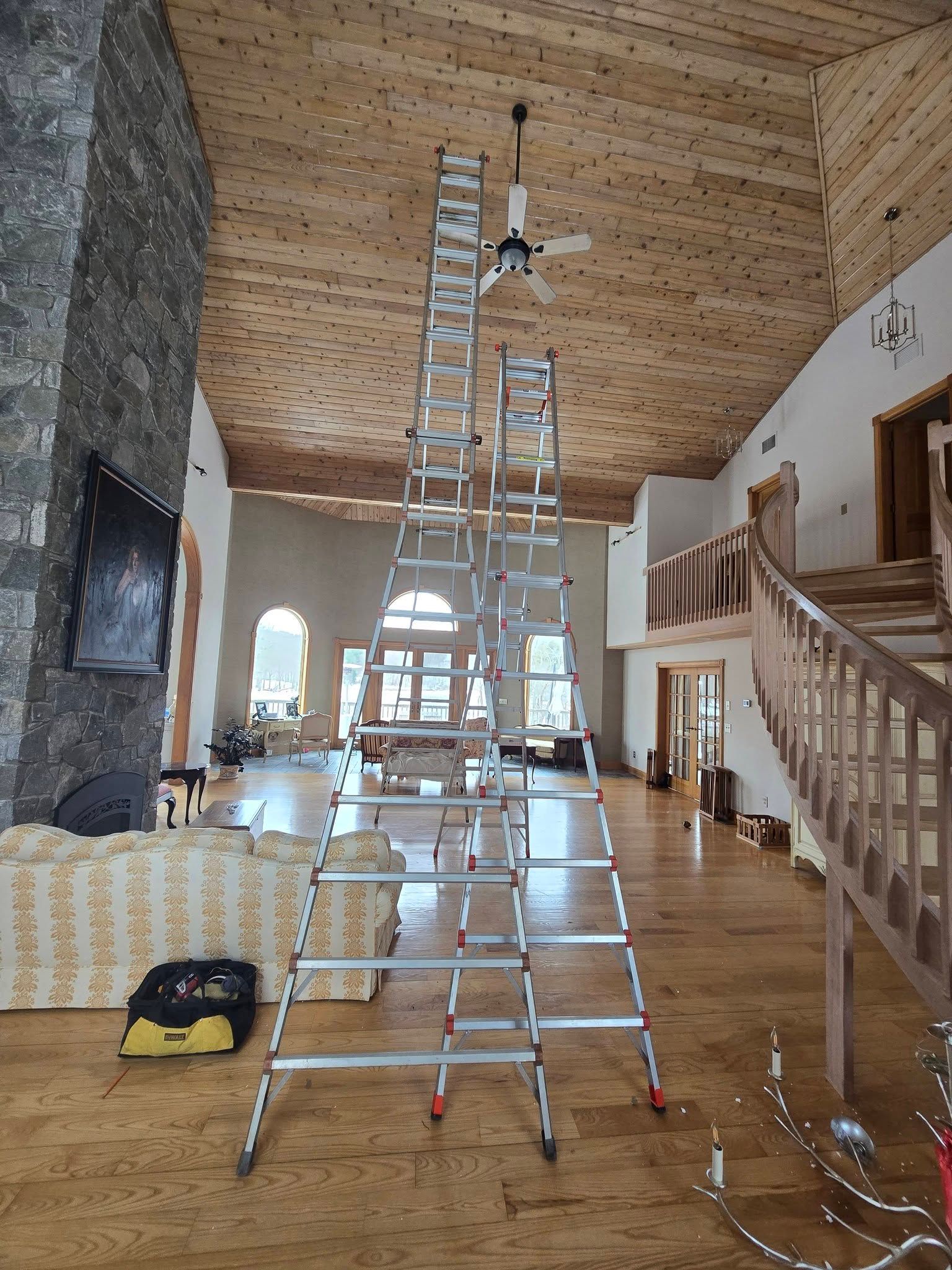 Tall ladder in a wood-paneled room with a vaulted ceiling and stone fireplace.