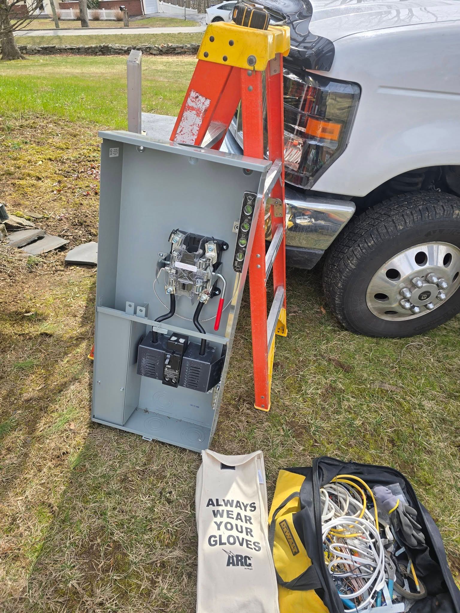 Open electrical panel beside an orange ladder and parked car, with tools and wires on the grass.