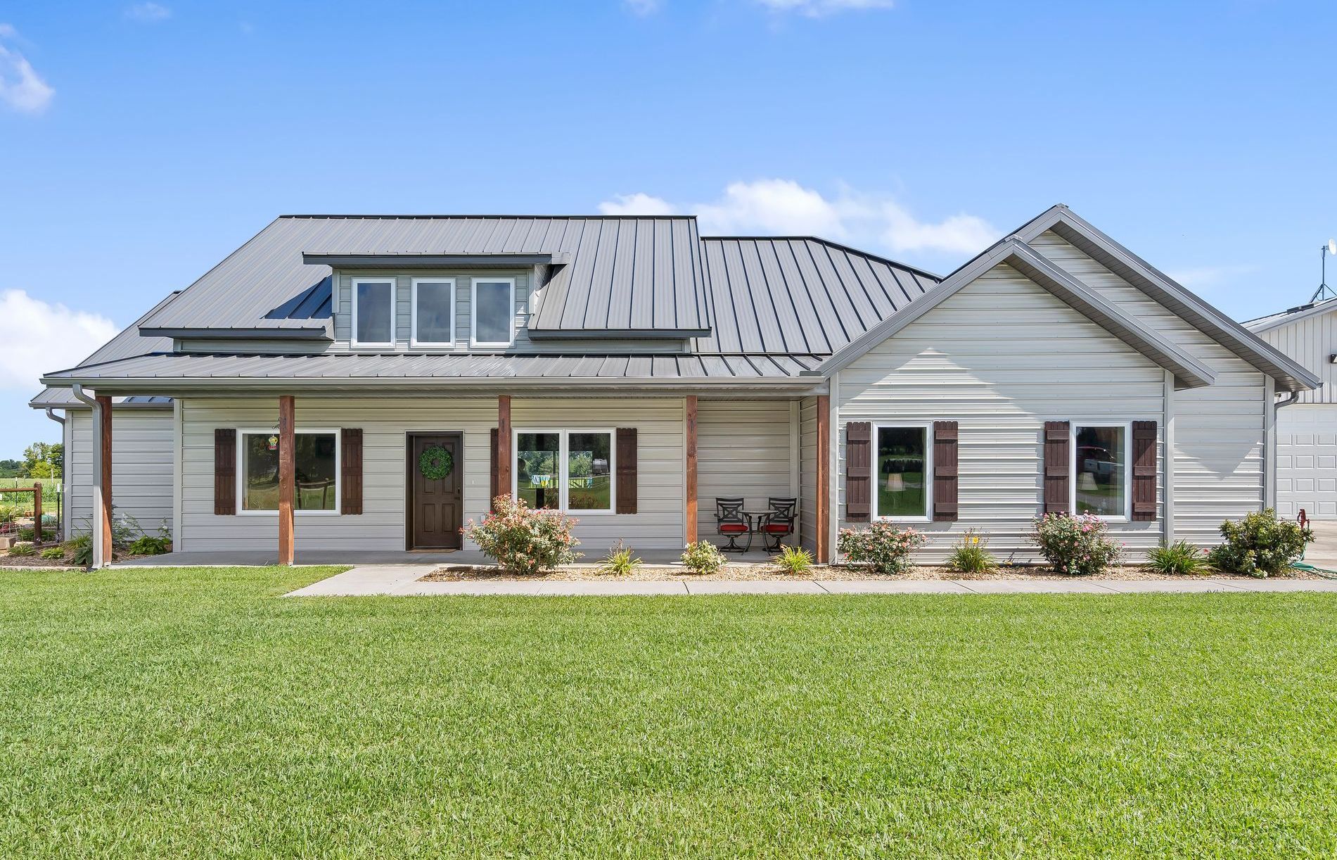 A large ICF farmhouse with a metal roof is sitting in a lush green field | Rogers AR Builders
