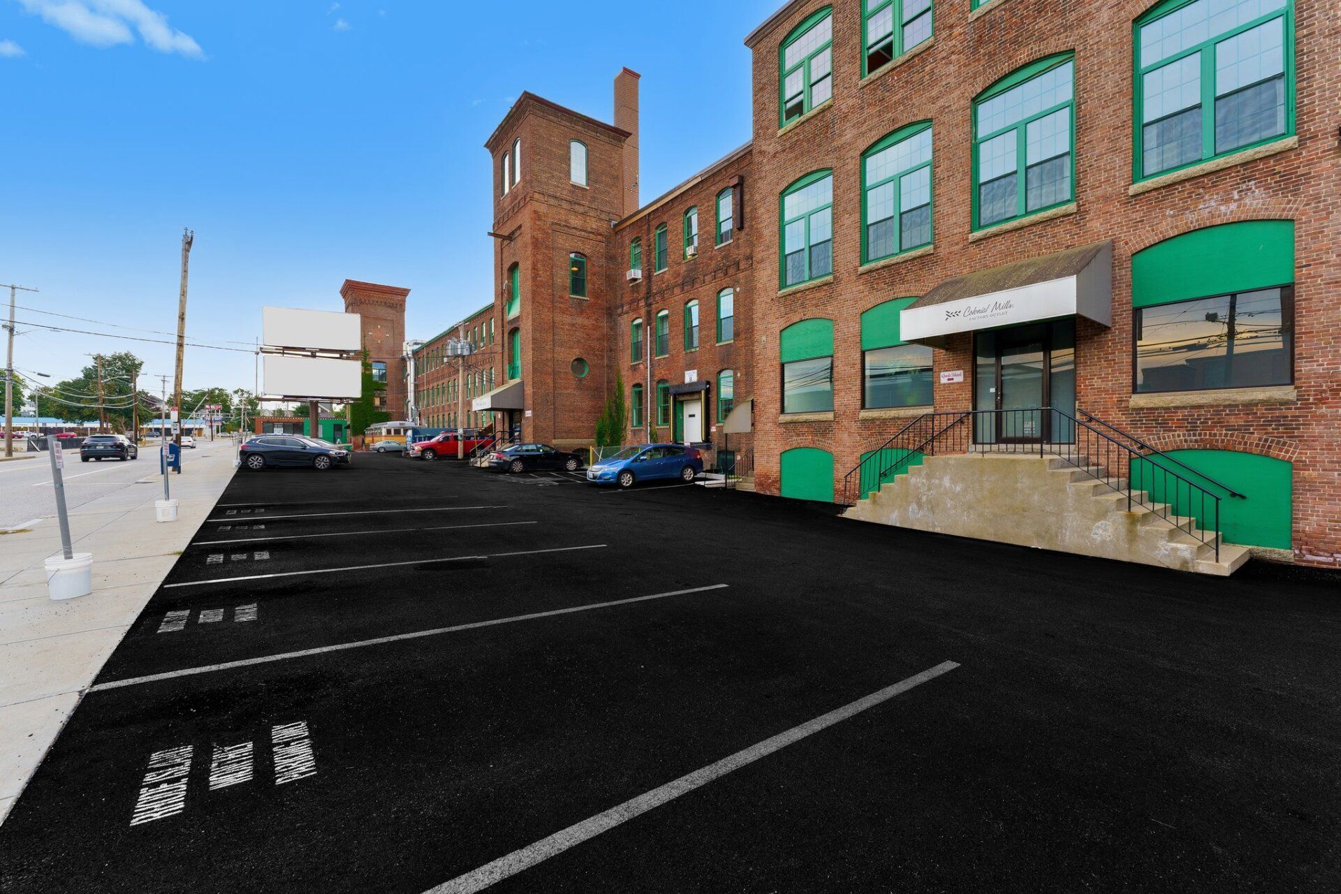 A parking lot in front of a brick building with green awnings