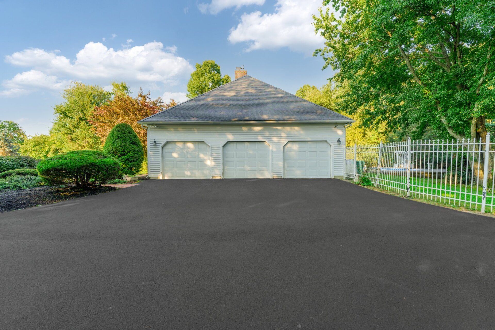 A large white garage with two garage doors and a black driveway.