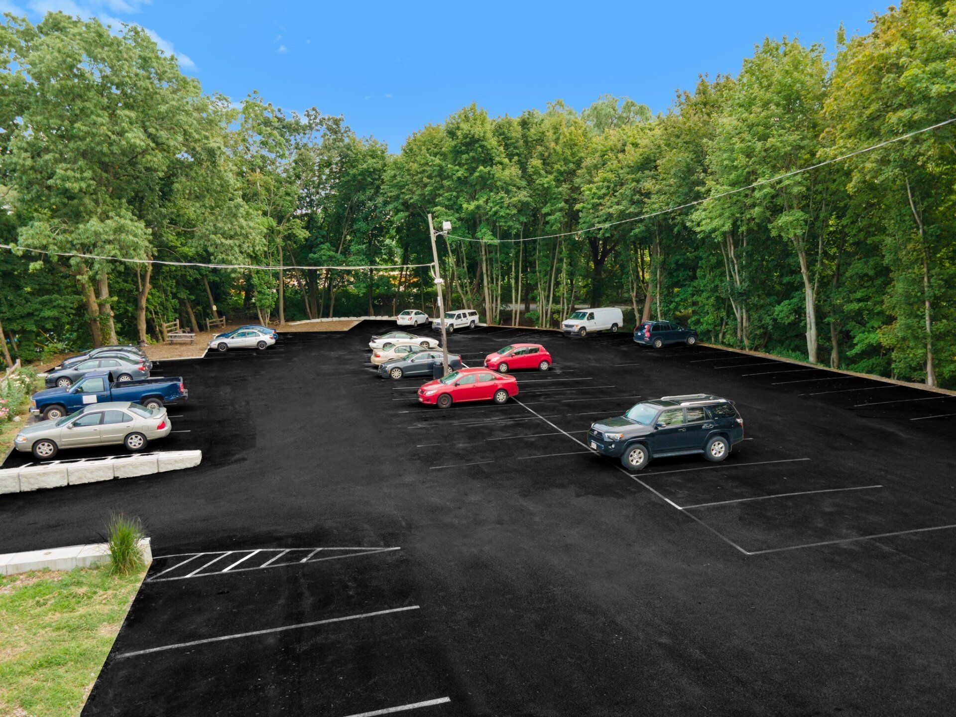 A lot of cars are parked in a parking lot with trees in the background