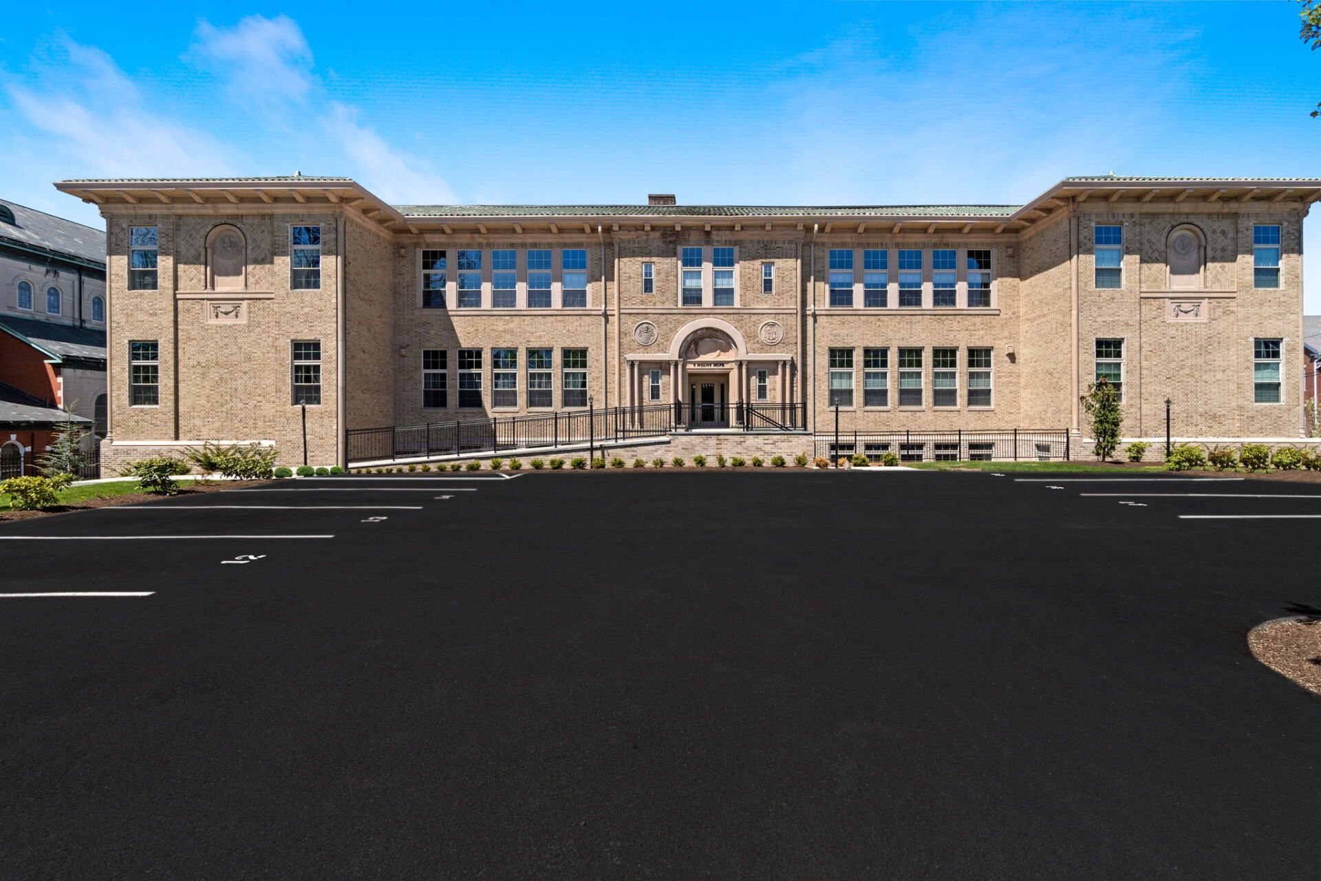 A large building with a lot of windows is sitting on the side of a road.
