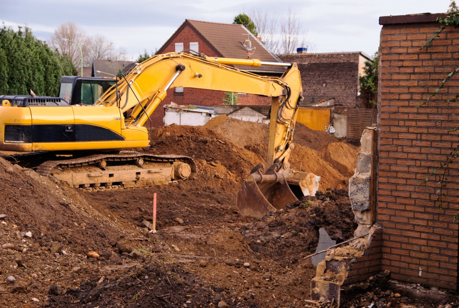 A yellow excavator is digging a hole in the dirt at a construction site.