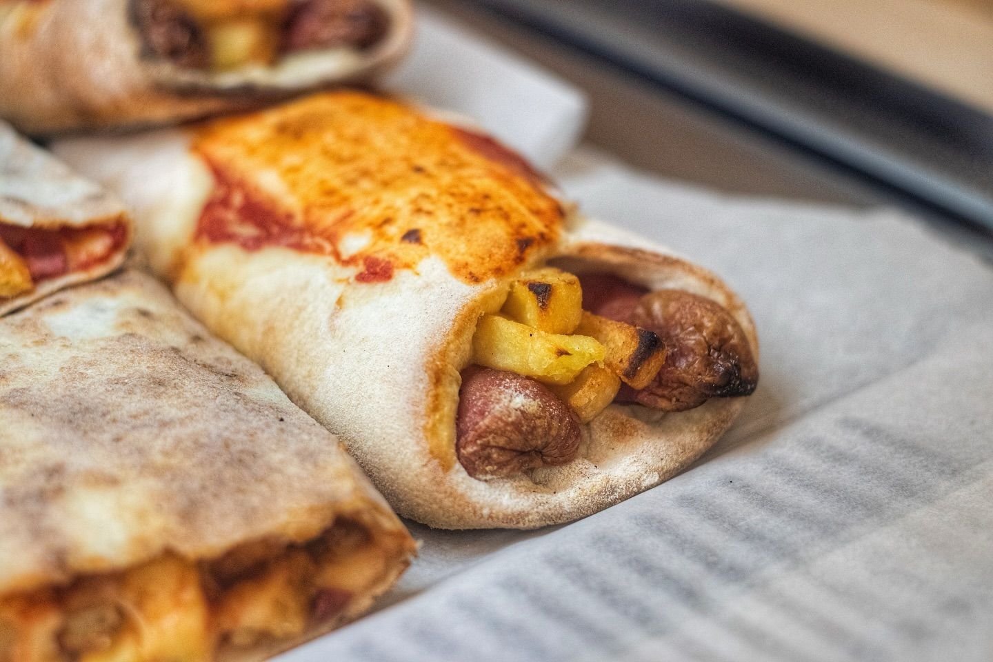 Un primo piano di una pizza wrap con salsiccia e formaggio su un giornale.