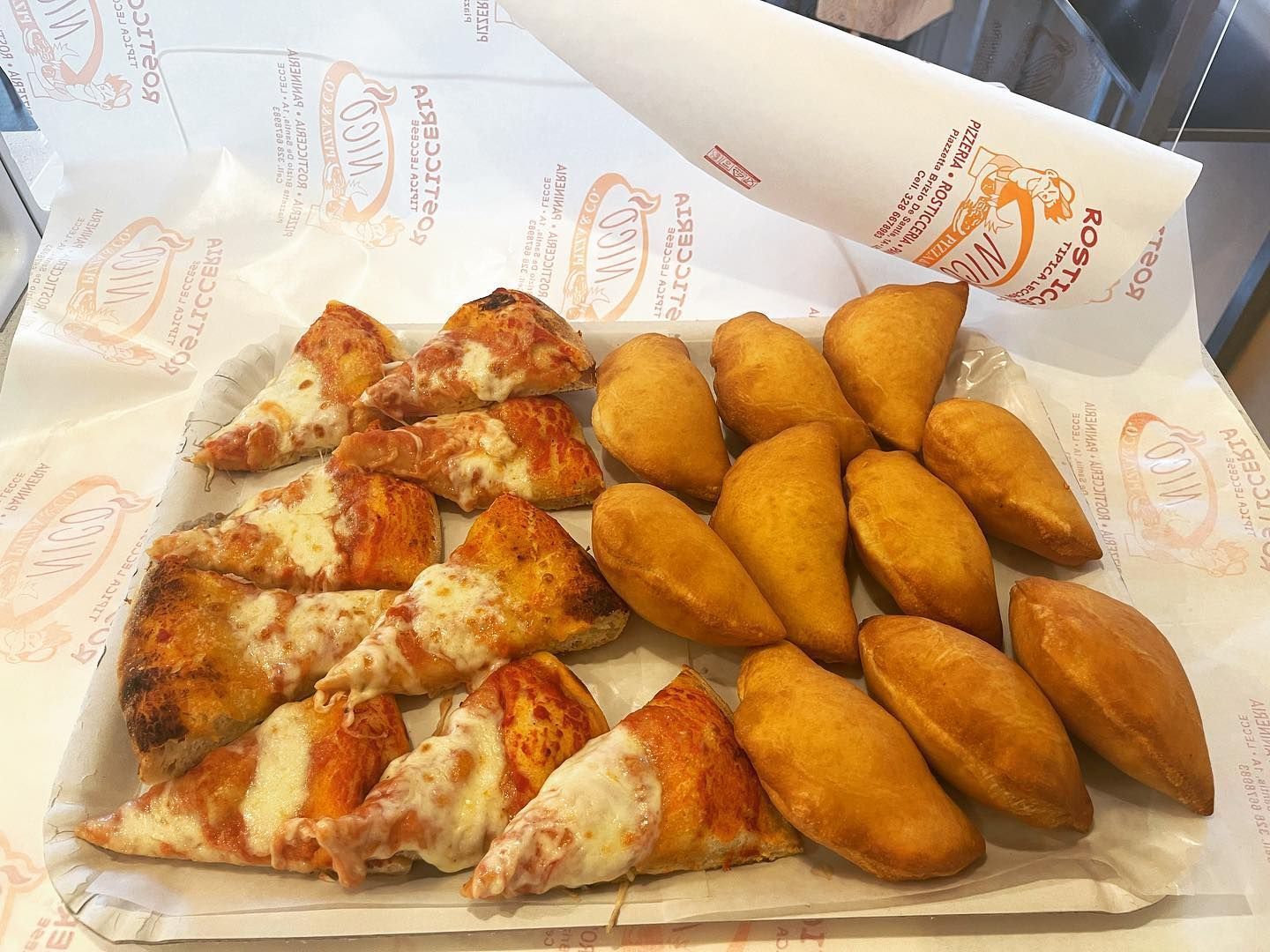 Un piatto di carta ricoperto di fette di pizza e cibo fritto.