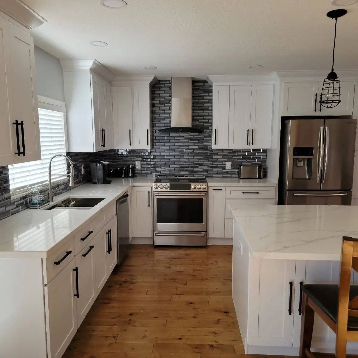 Bright modern kitchen with island seating, stainless fridge, and pendant lights
