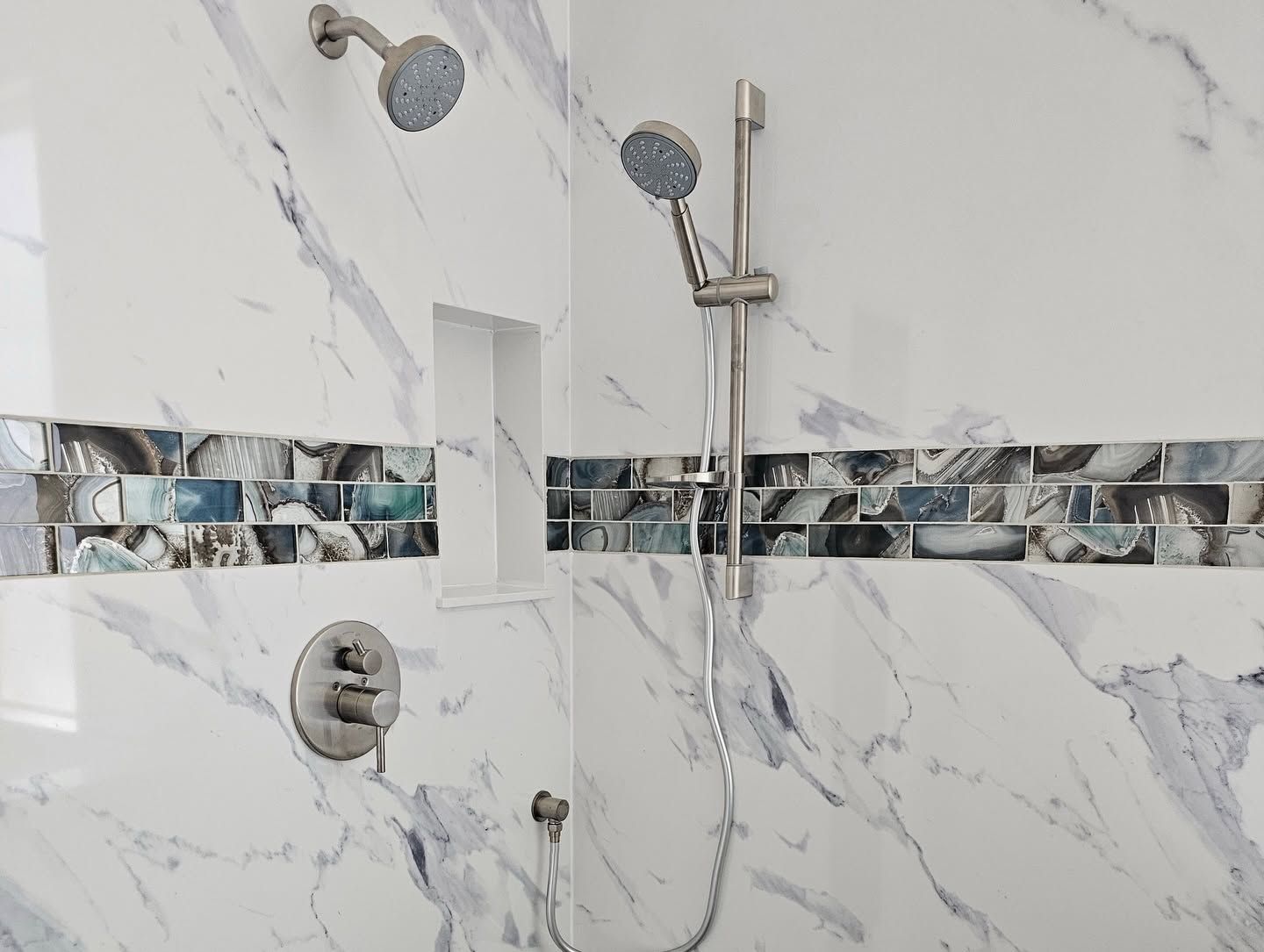 Modern bathroom with glass shower, white tile, and gray built-in cabinets