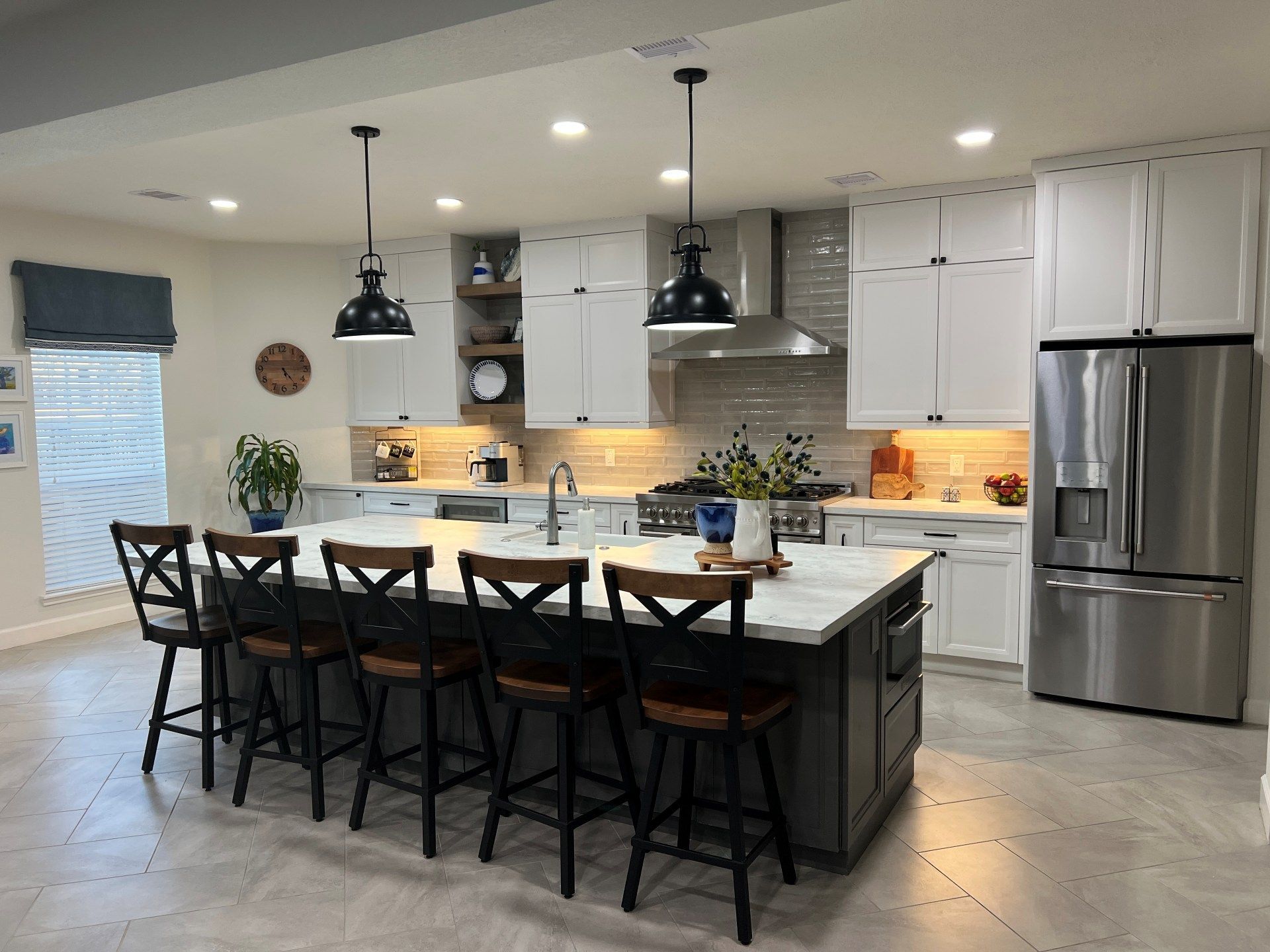 Bright modern kitchen with island seating, stainless fridge, and pendant lights