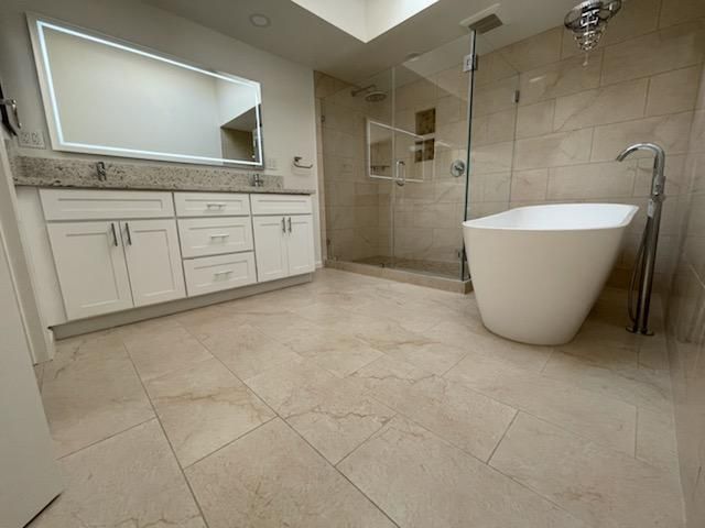 Modern bathroom with glass shower, white tile, and gray built-in cabinets