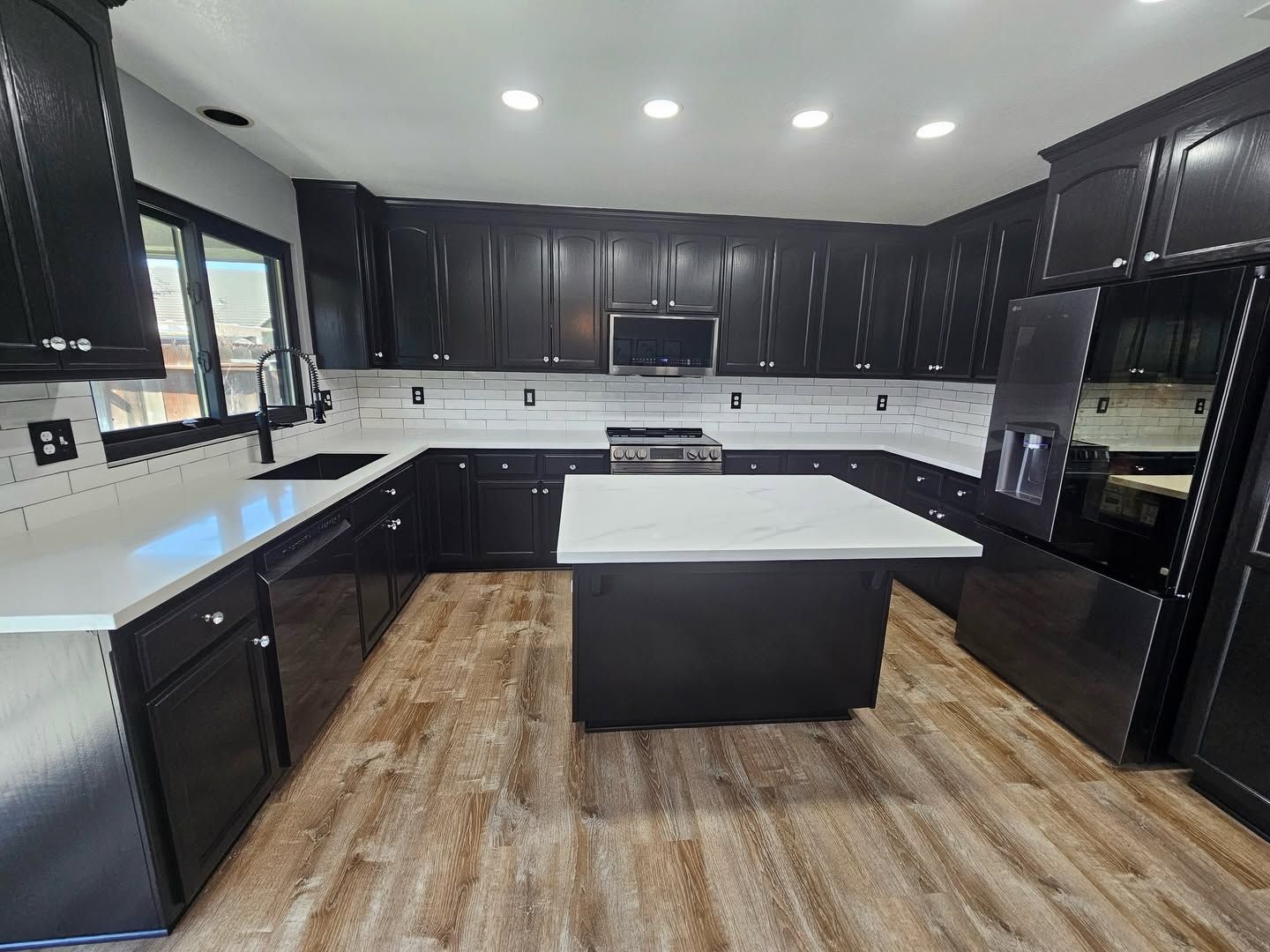 Bright modern kitchen with island seating, stainless fridge, and pendant lights