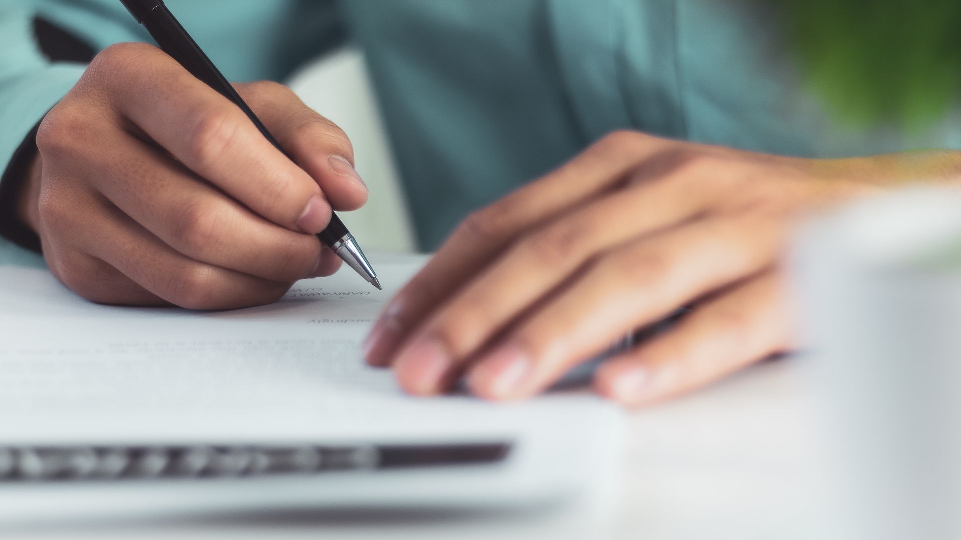 a person is writing on a piece of paper with a pen .