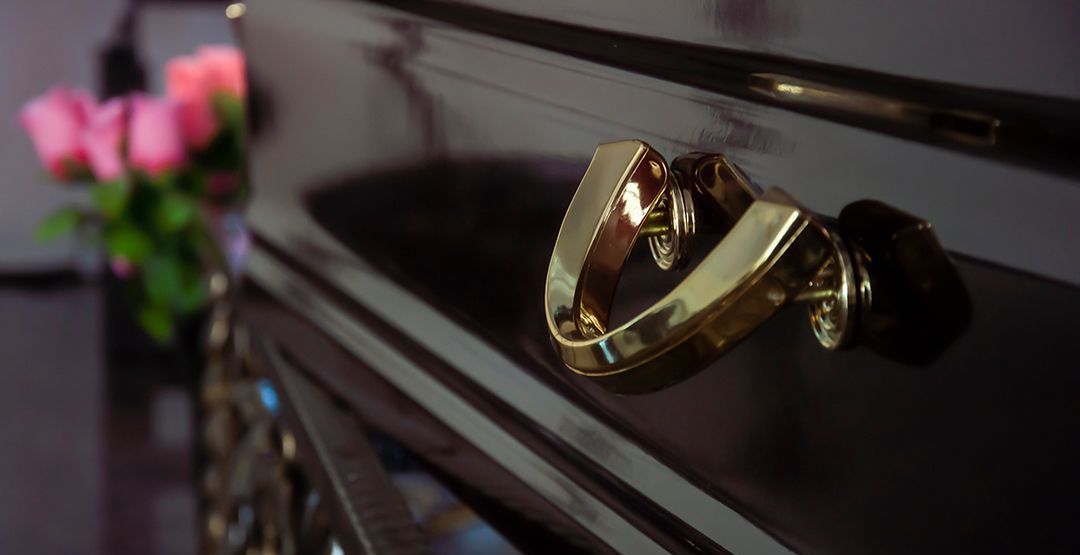 a close up of a gold handle on a black cabinet with flowers in the background .