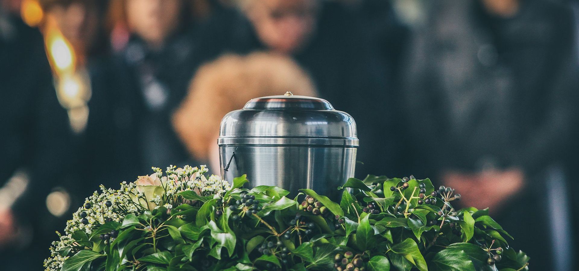 a urn is sitting on top of a wreath of leaves at a funeral .