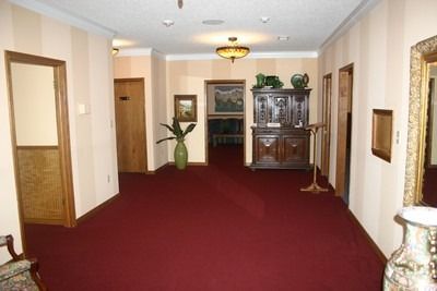 Empty hallway with red carpet, white walls, and wooden furniture along the far end.