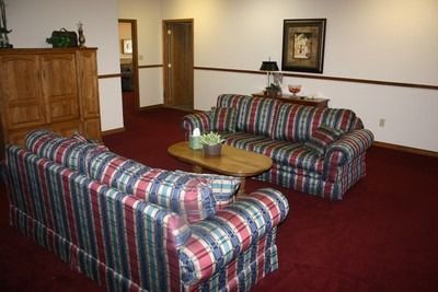 Hotel lounge with two plaid sofas, wooden table, red carpet, and framed wall art