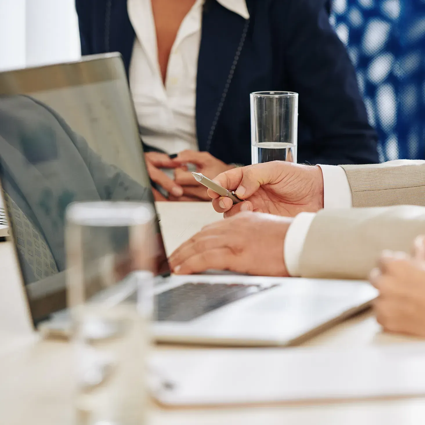 Hands of mature businessman with pen in his hand sitting at table in meeting room