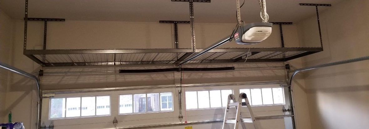 Ceiling-mounted garage door opener and rails in a room with a ladder and windows below.
