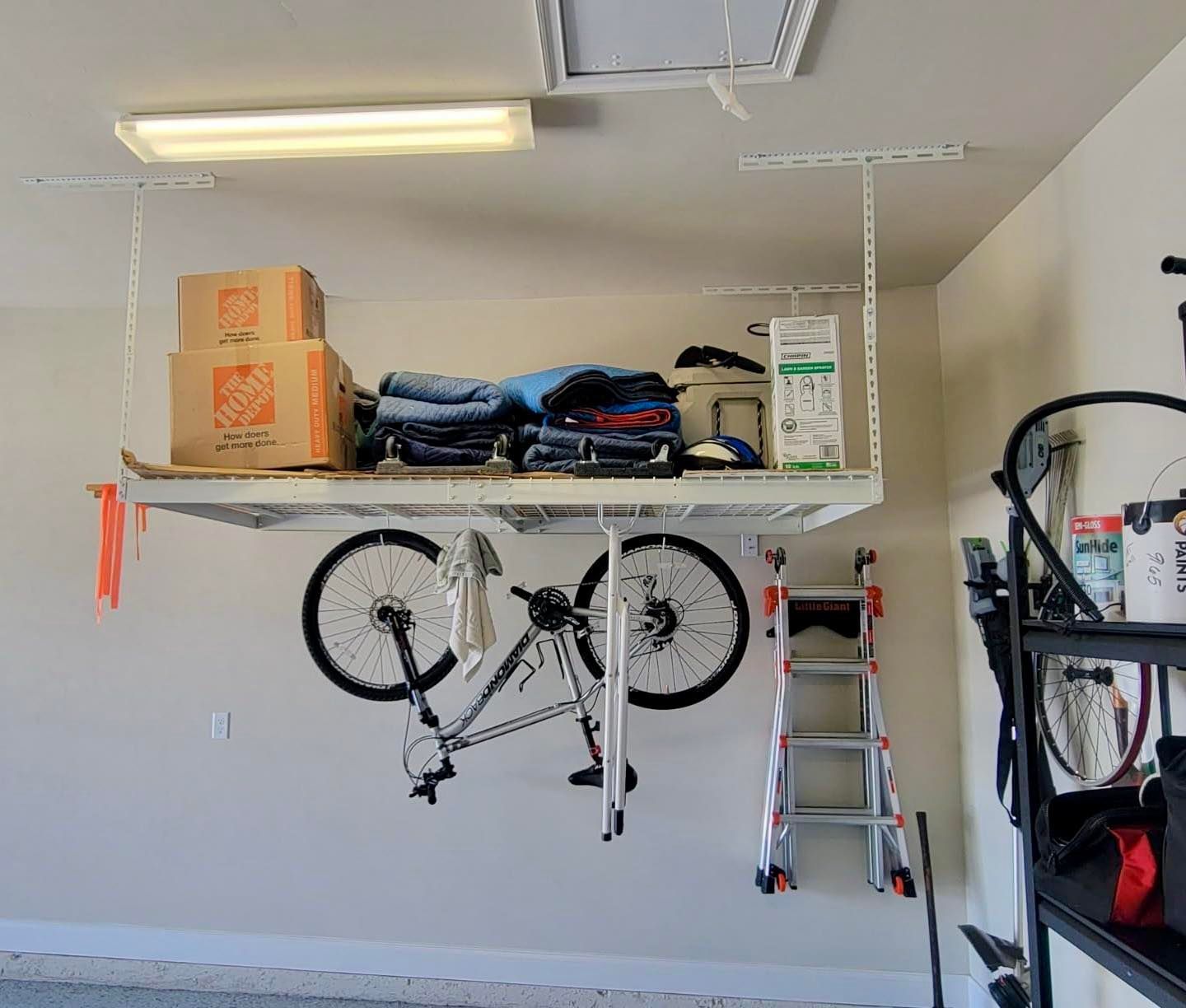 Garage storage wall with hanging bicycle, shelves, ladder, and boxes