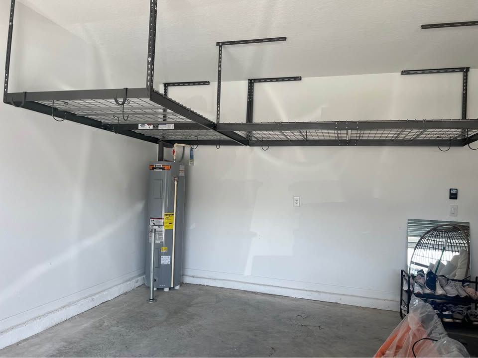 Garage interior with overhead metal storage racks and a water heater against a white wall