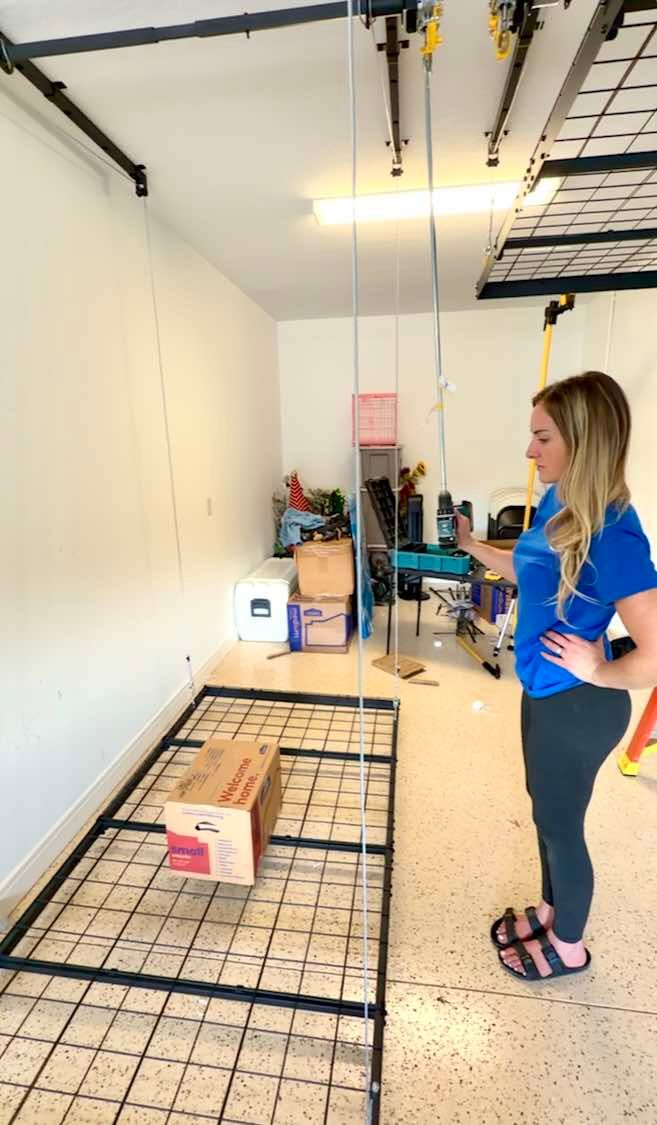 Woman in blue shirt stands beside a wall-mounted grid of tiles in a bright room